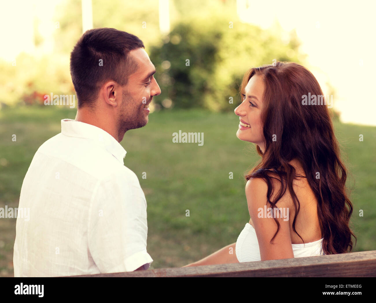 smiling couple sitting on bench in park Stock Photo - Alamy