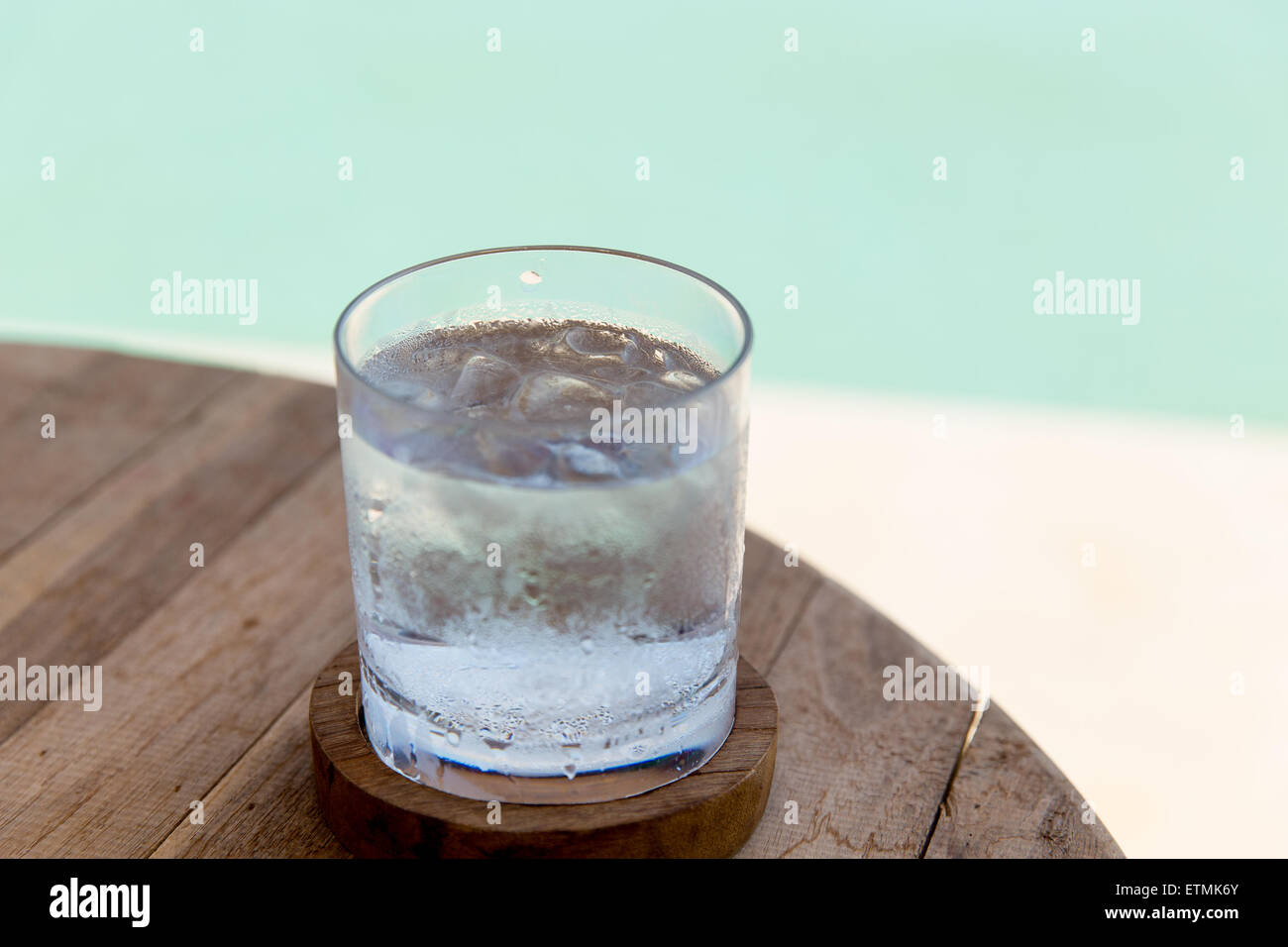 glass of water with ice cubes on table at beach Stock Photo