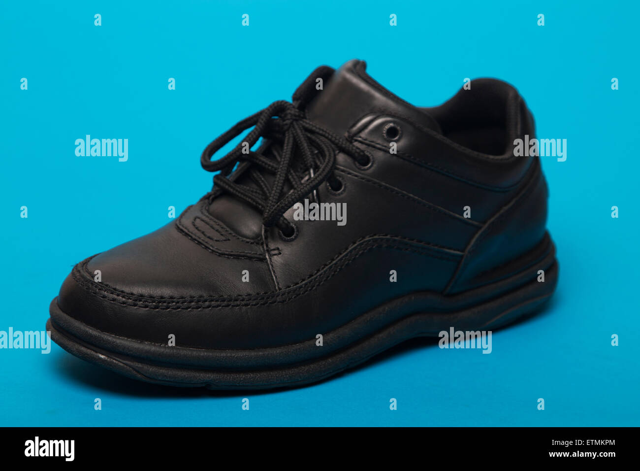Close up view of a black shoe isolated on a blue background. Stock Photo