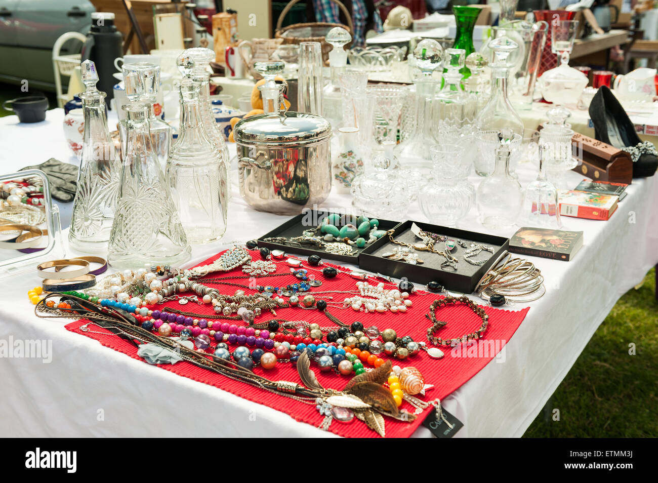 Typical display of household items for sale laid out on table at car boot fair nick knacks glasses jewelery glass wooden plane Stock Photo