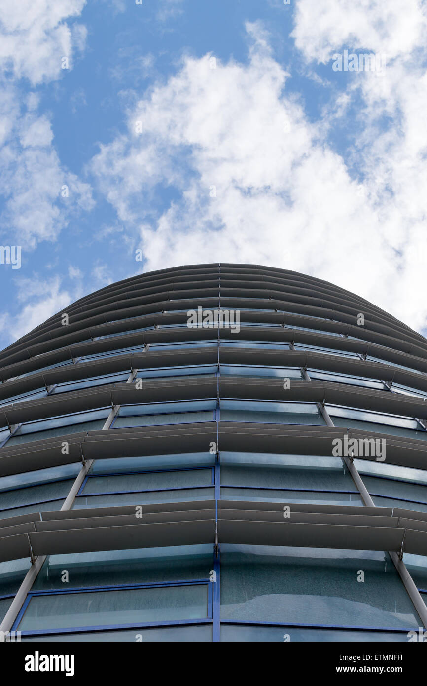Glass windowed modern business building against a blue sky and clouds ...