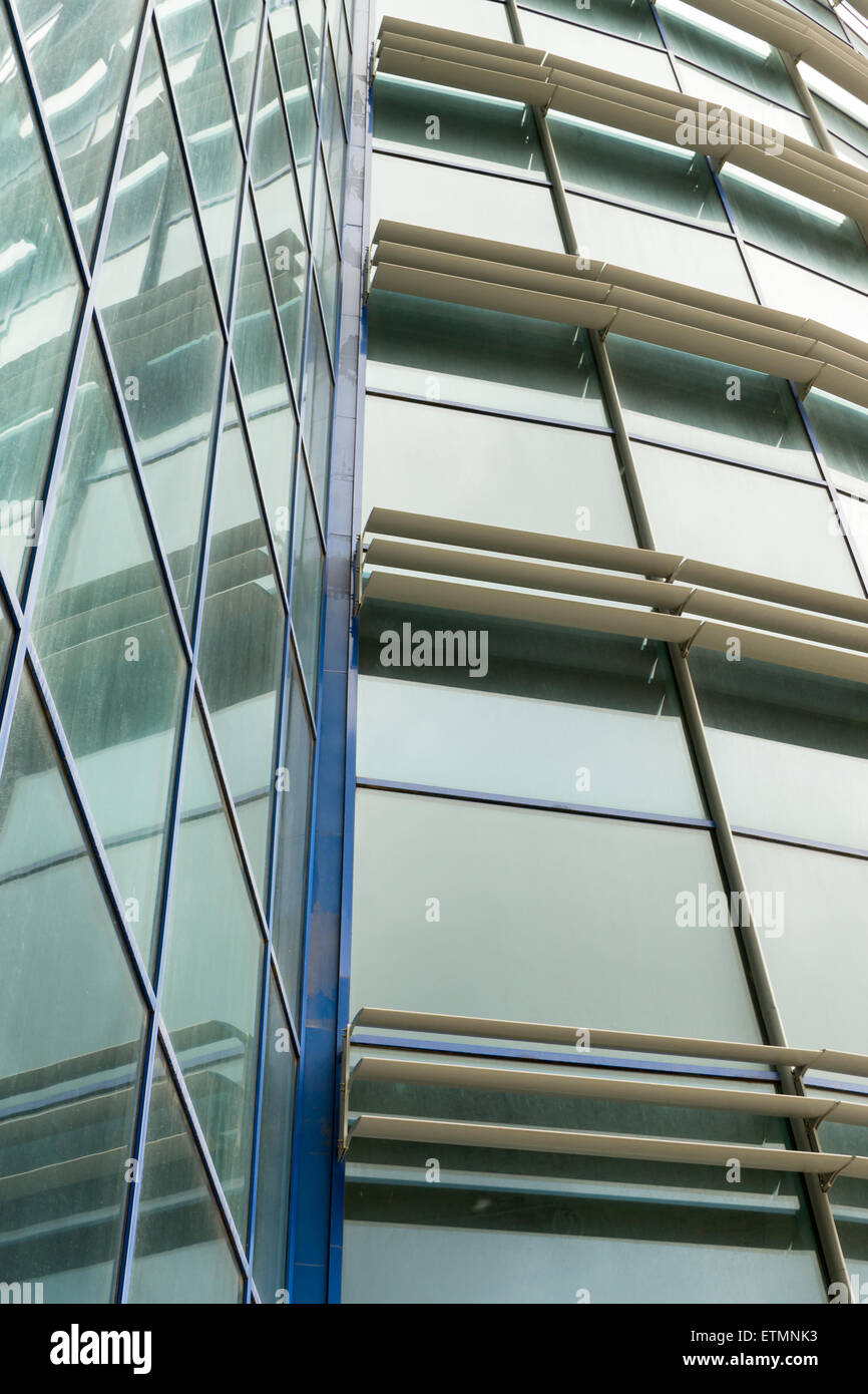 Looking up at a modern style building with glass angled wall and ...