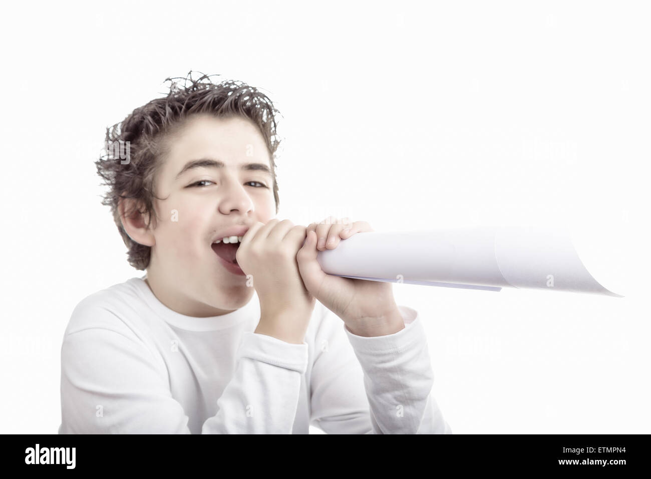 Handsome smiling hispanic boy with medium length hair and questioning eyes shouts in a fake megaphone made with white paper Stock Photo