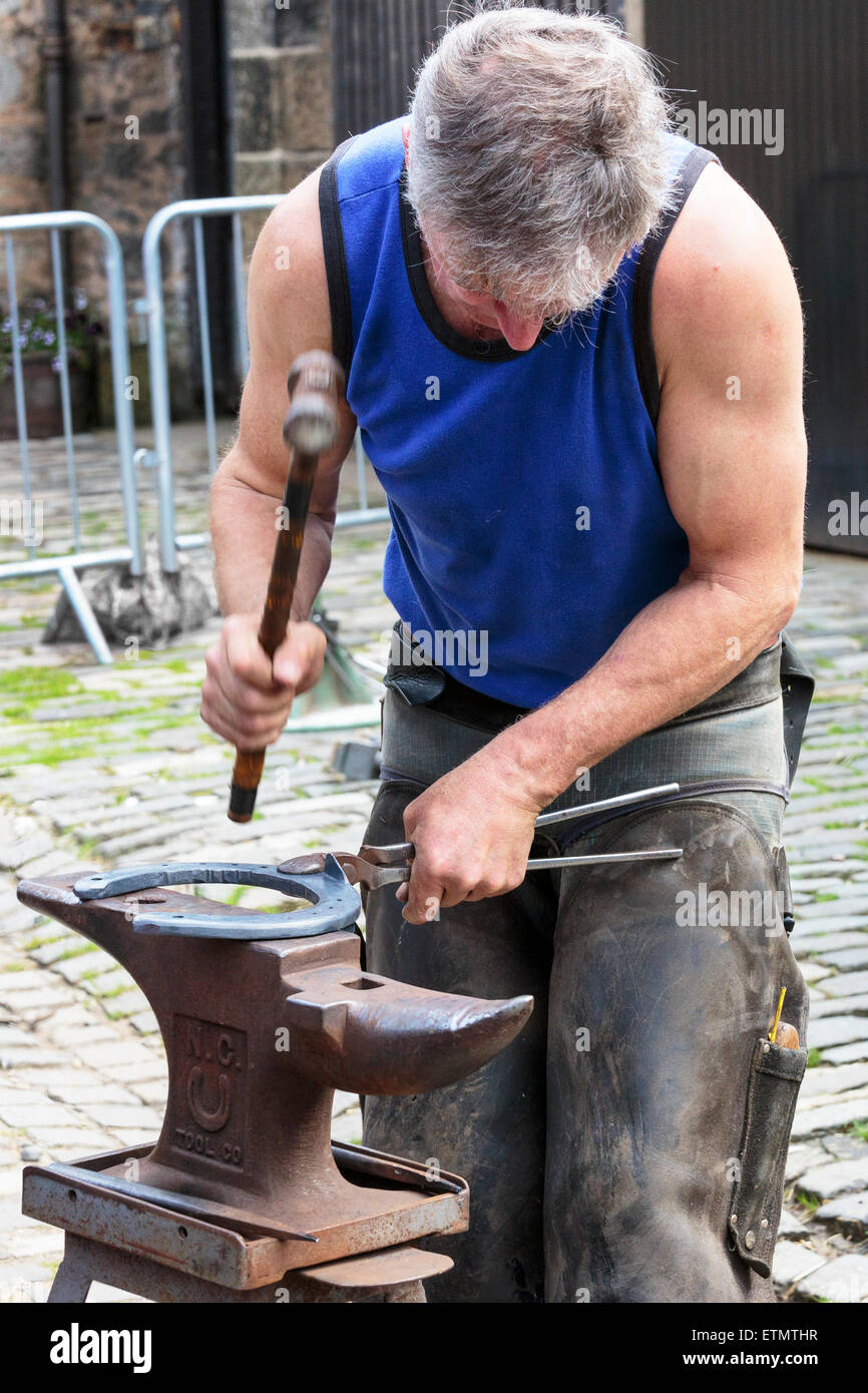 Farrier making a horseshoe and moulding it over an anvil while it was still red hot. Pollok Park, Glasgow, Scotland, UK Stock Photo