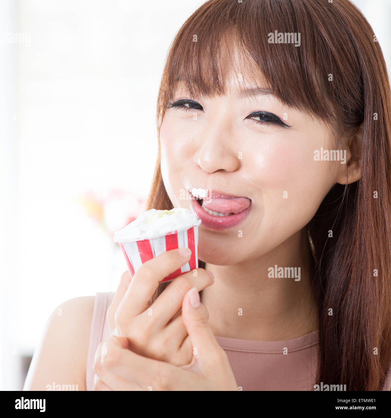 Portrait Of Attractive Asian Girl Eating Cupcake And Licking On Her Lips Young Woman Indoors 