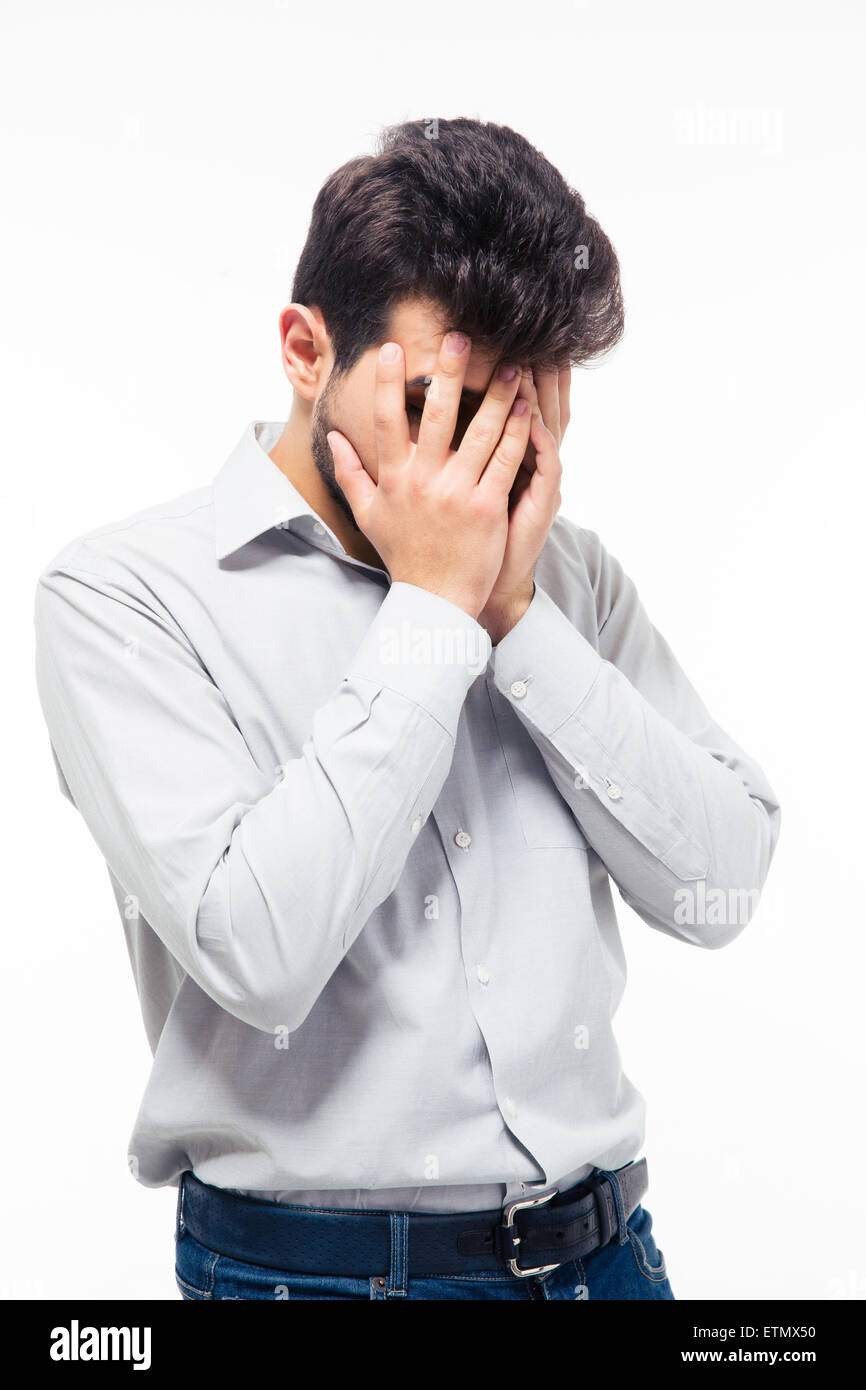 Depressed young man covering his face isolated on a white background ...