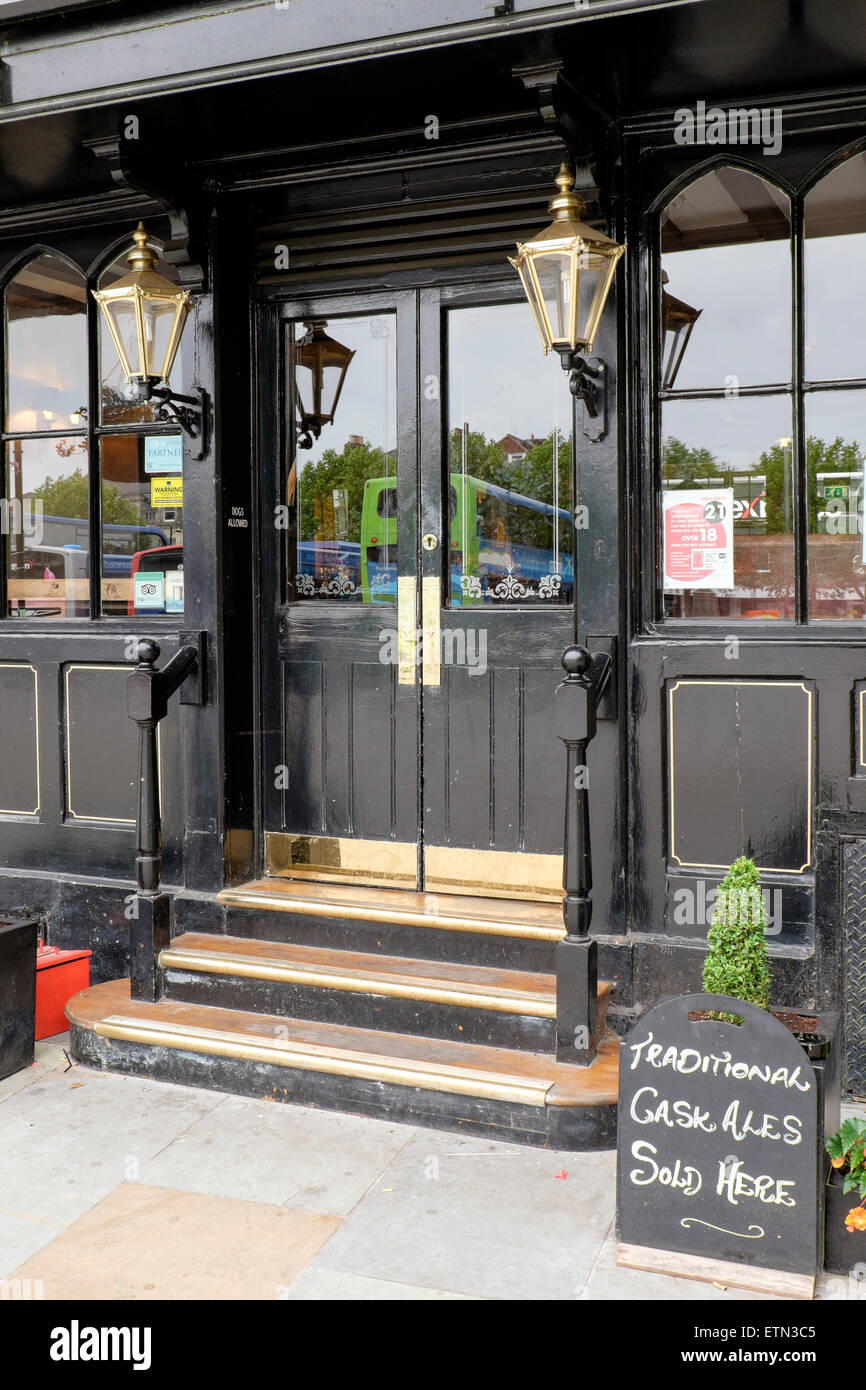 Traditional UK pub entrance with black pained doors and brass furniture and carriage lamps Stock Photo