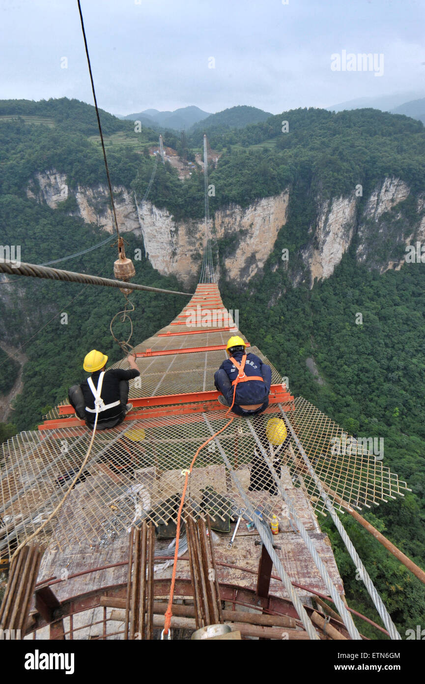 Zhangjiajie, China's Hunan Province. 15th June, 2015. Workers build the vitreous bridge above the grand canyon in Zhangjiajie, central China's Hunan Province, June 15, 2015. A giant new vitreous bridge is currently under construction across the 400-metre deep Zhangjiajie Grand Canyon in Hunan province. The bridge will stretch 430 metres between its support pillars, making it a new scenic spot for tourism in the world. Credit:  Long Hongtao/Xinhua/Alamy Live News Stock Photo