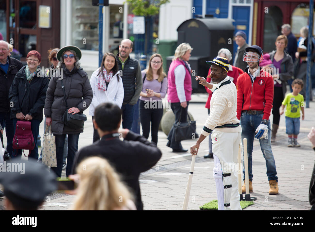 Street theatre group performing a cricket piece in Warwick town centre Spring 2015 Stock Photo