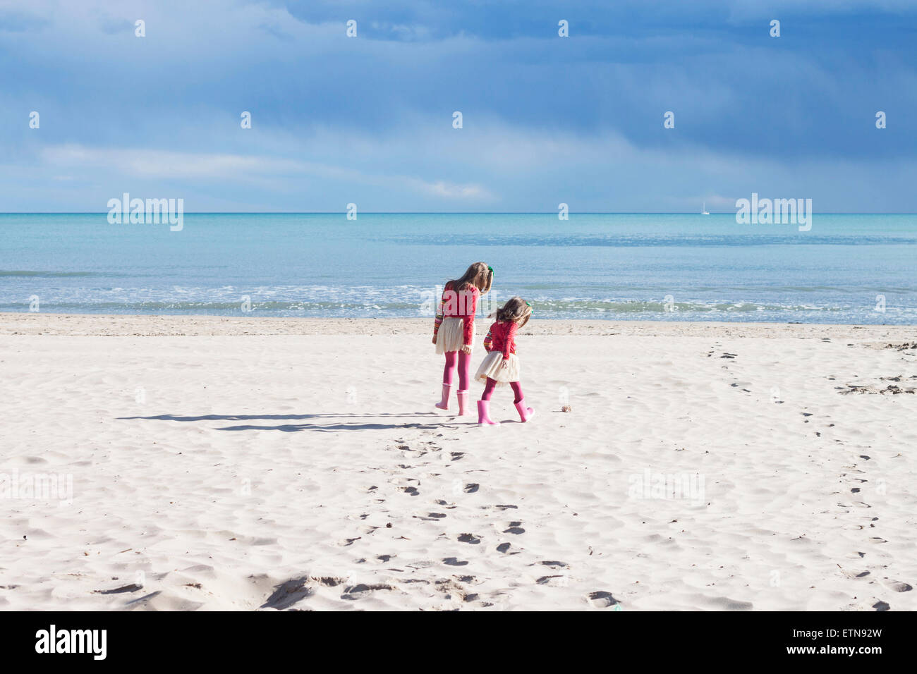 Rear view of two girls walking on the beach Stock Photo