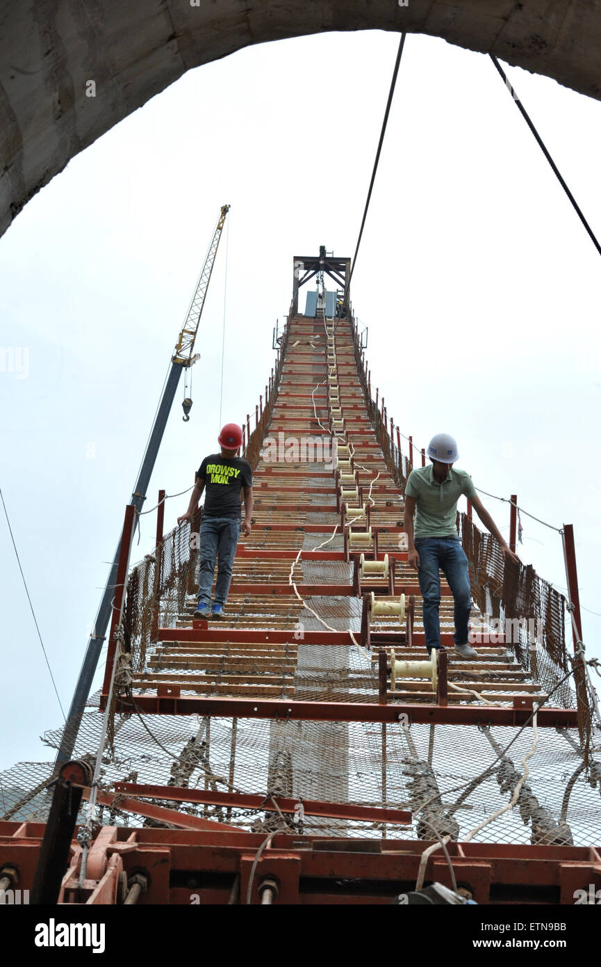 Zhangjiajie, China's Hunan Province. 15th June, 2015. Workers check the guardrail at the construction site of the vitreous bridge above the grand canyon in Zhangjiajie, central China's Hunan Province, June 15, 2015. A giant new vitreous bridge is currently under construction across the 400-metre deep Zhangjiajie Grand Canyon in Hunan province. The bridge will stretch 430 metres between its support pillars, making it a new scenic spot for tourism in the world. Credit:  Long Hongtao/Xinhua/Alamy Live News Stock Photo