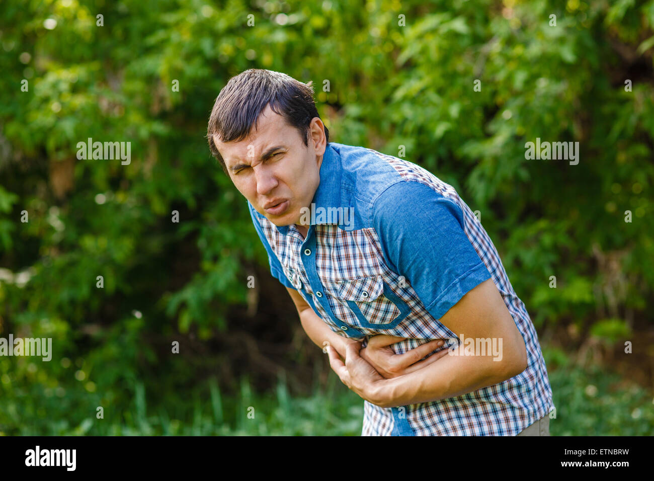 Man on the street abdominal pain on a green background leaves Stock