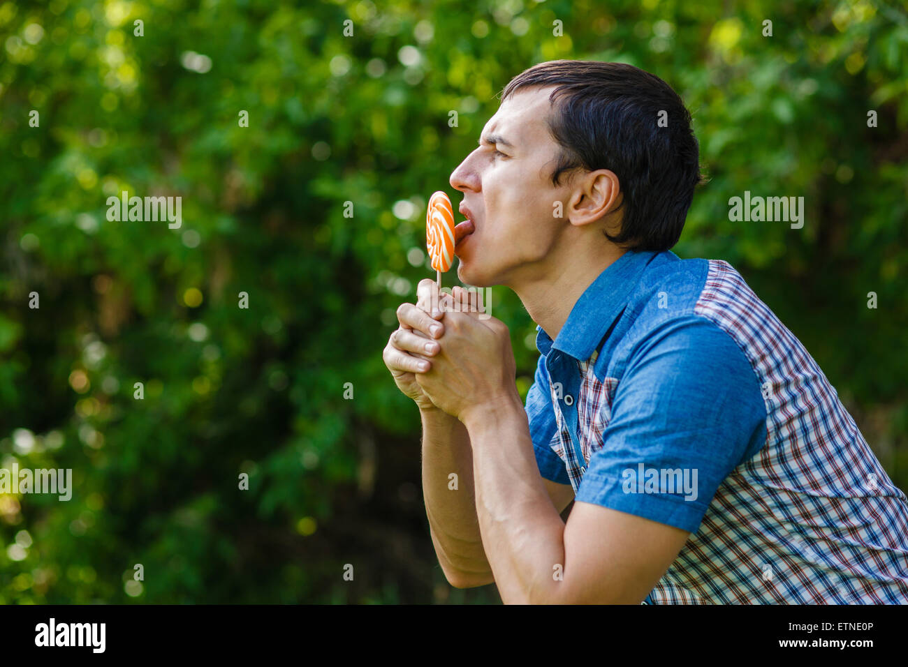 The man in the street holding a lollipop on a green background Stock Photo