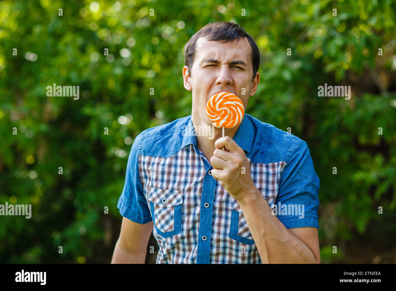 The man in the street holding a lollipop on a green background l Stock Photo