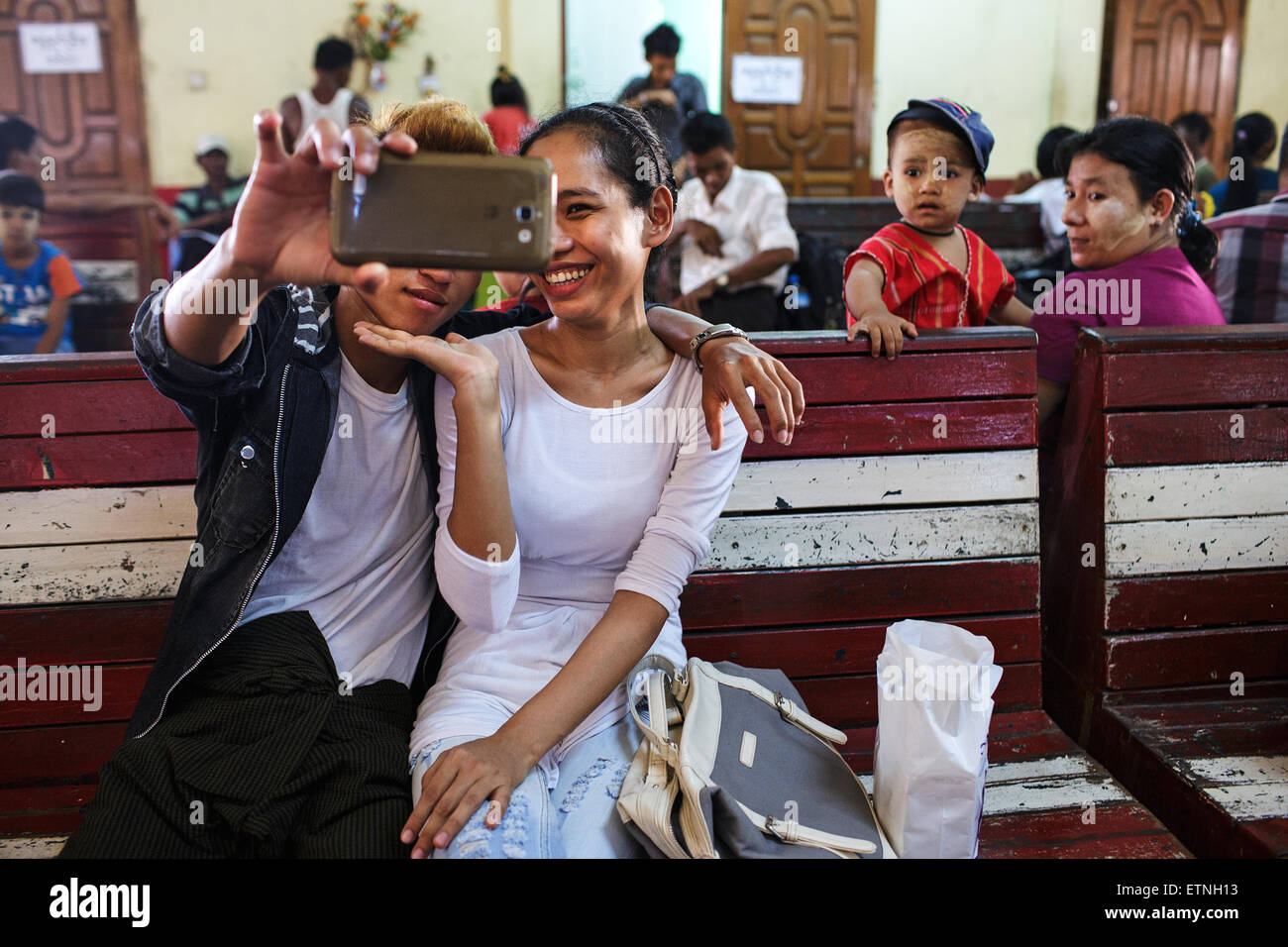 A young couple taking a selfie on their smartphone in Yangon, Myanmar (Burma) Stock Photo