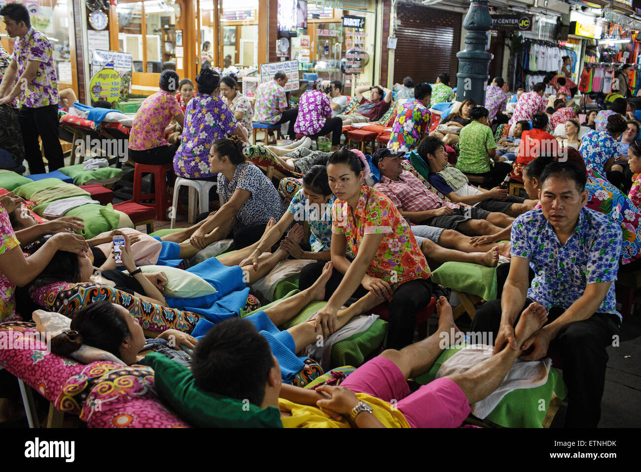 Foreign tourists having massage at night on Khao San road in Bangkok, Thailand. Stock Photo