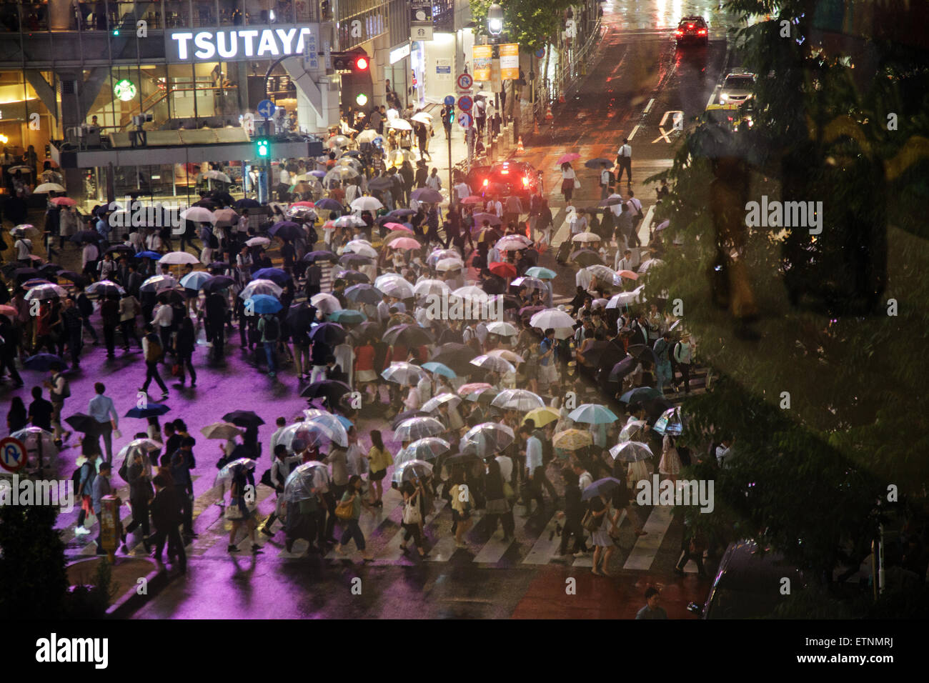 People with umbrellas on a rainy night crossing the road intersection ...