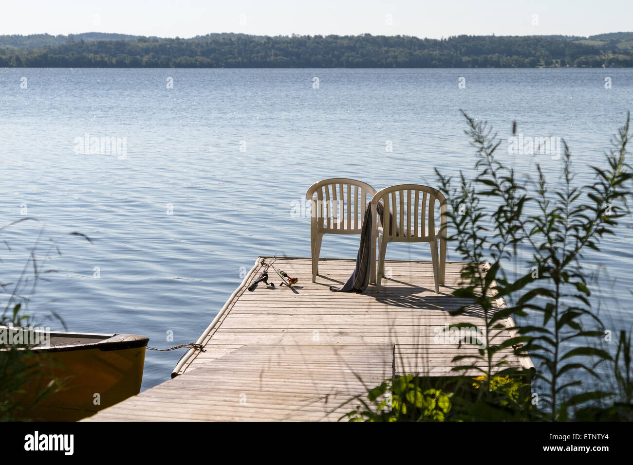 two chairs on a wooden deck by the lake with fishing rods Stock Photo -  Alamy
