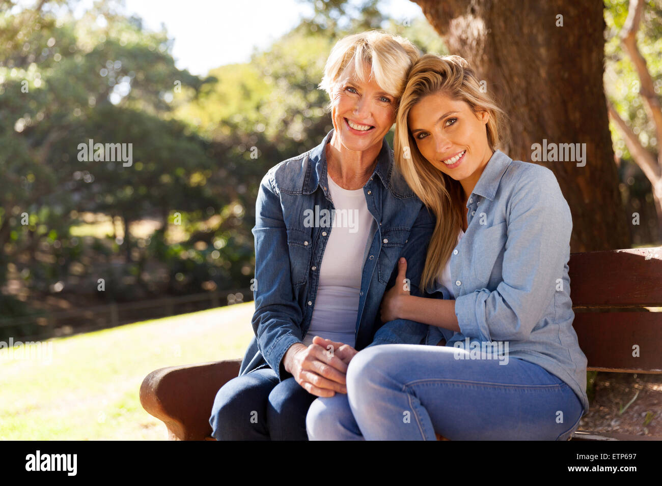 young daughter and mother sitting on bench and relaxing in the park Stock Photo