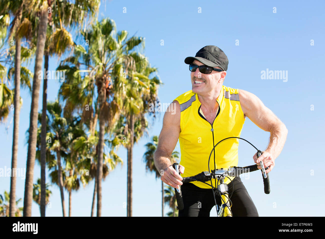 man on his bicycle in front of palm trees Stock Photo