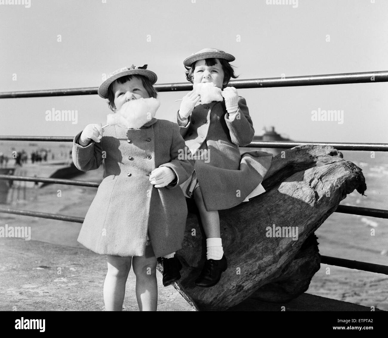 Sisters Susan (4) Hazel (3) McKinley of Leasowe, Wirral, complete with Easter bonnets and a fistful of candyfloss on prom at New Brighton, Merseyside. 1st April 1959. Stock Photo