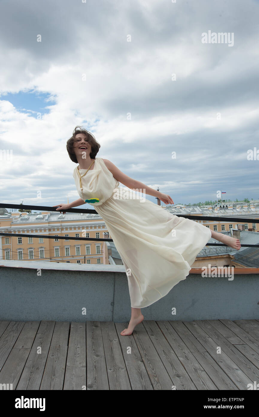 woman in white dress dancing on the roof barefoot Stock Photo