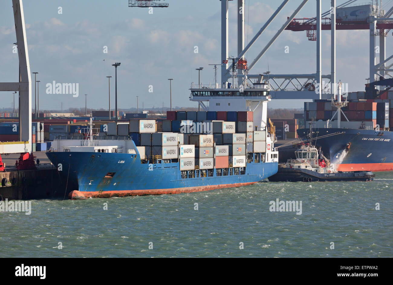 Tug boat assisting container ship by leaving Dunkerque Harbour Stock Photo