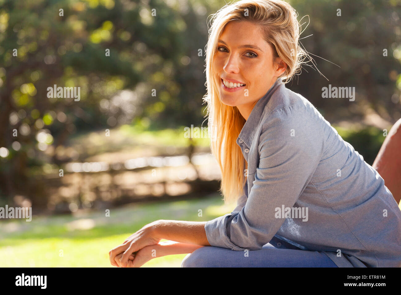 pretty young blond woman sitting at the park Stock Photo