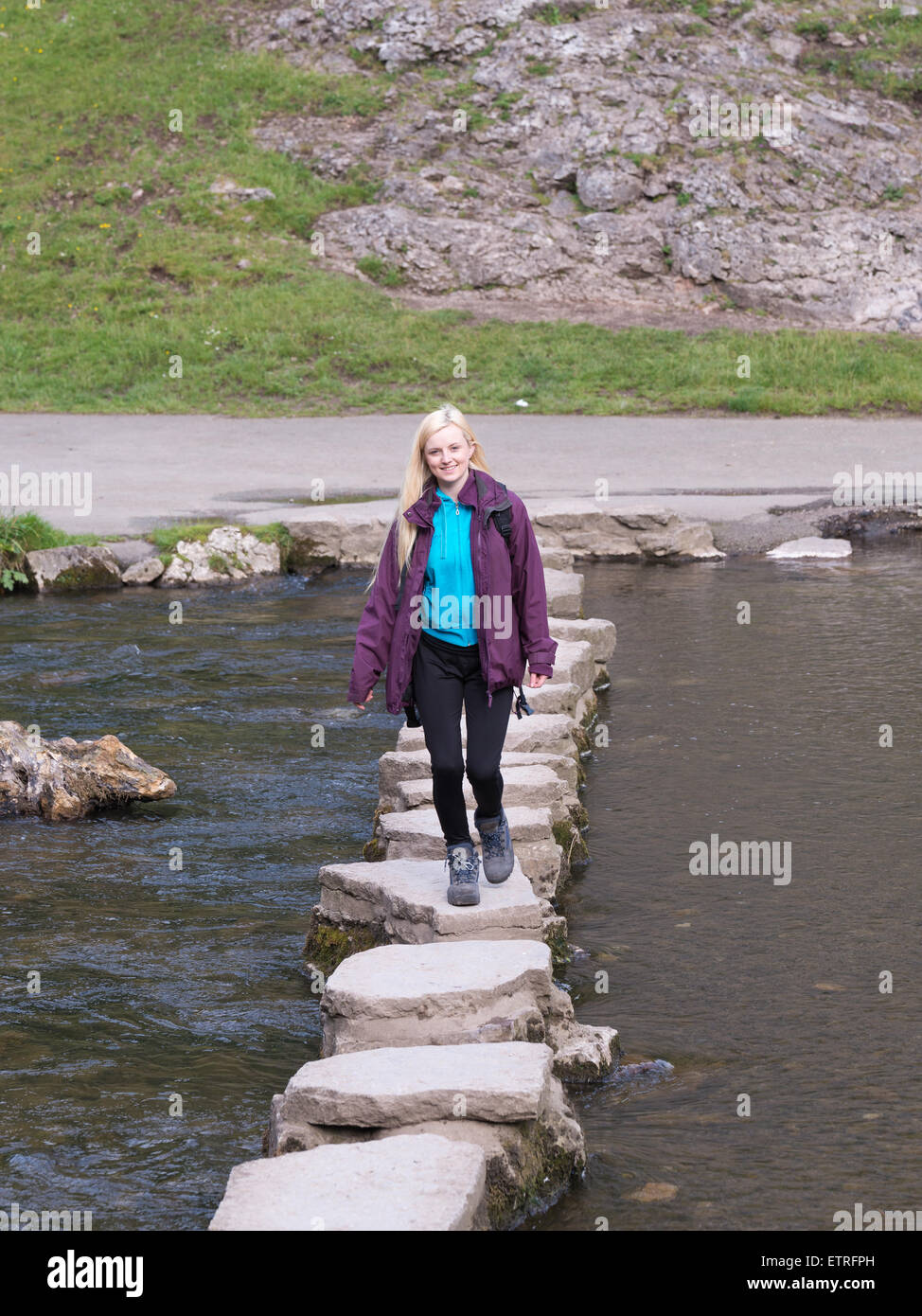 young female hiker crossing stepping stones in dovedale peak district Stock Photo