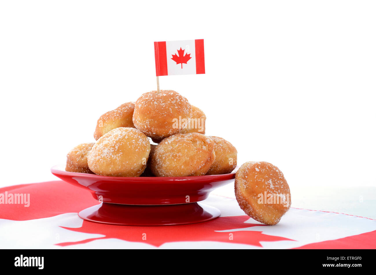 Stack of donut holes on red plate on Canadian maple leaf flag for Happy Canada Day celebration party. Stock Photo