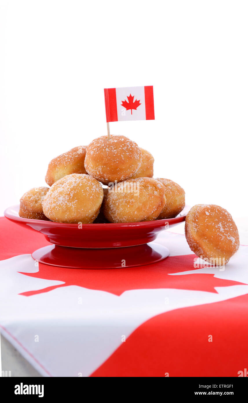 Stack of donut holes on red plate on Canadian maple leaf flag for Happy Canada Day celebration party. Stock Photo