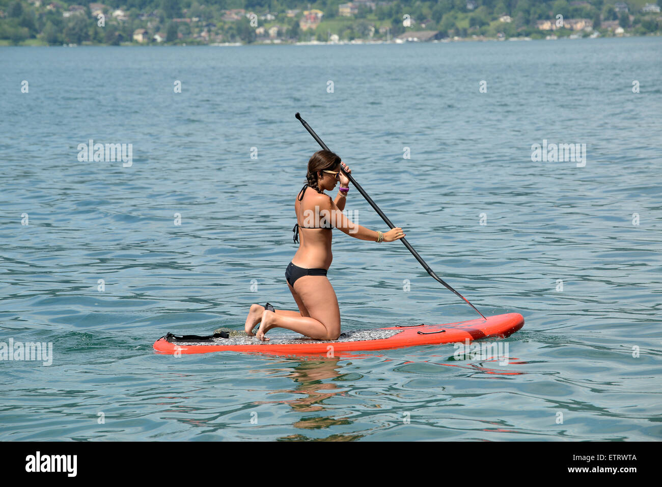 Woman in bikini Stand up paddle surfing or standing paddle boarding on Lake Annecy in France Stock Photo