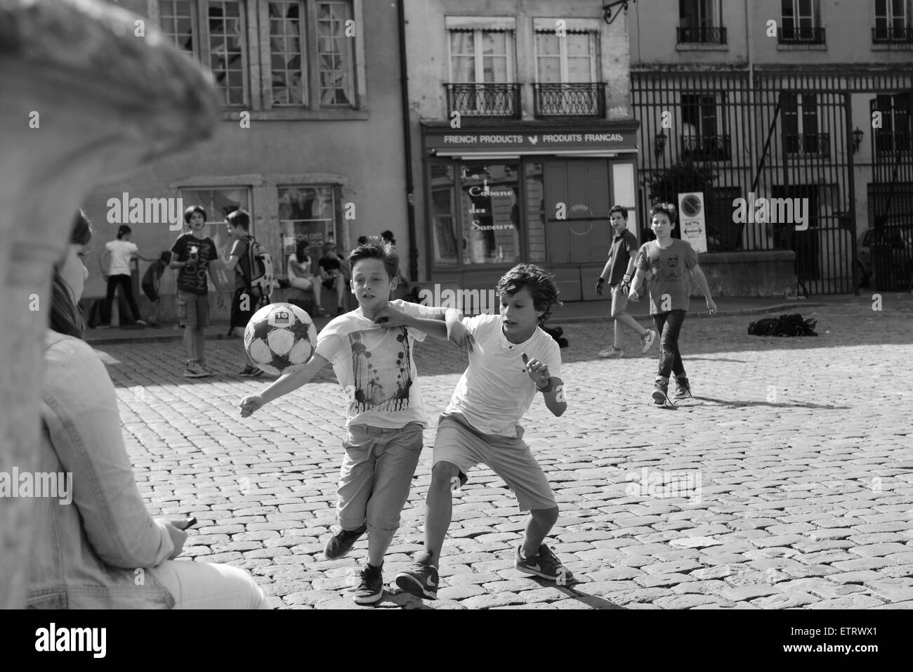 Children boys playing football on cobbled street in Lyon France Europe Stock Photo