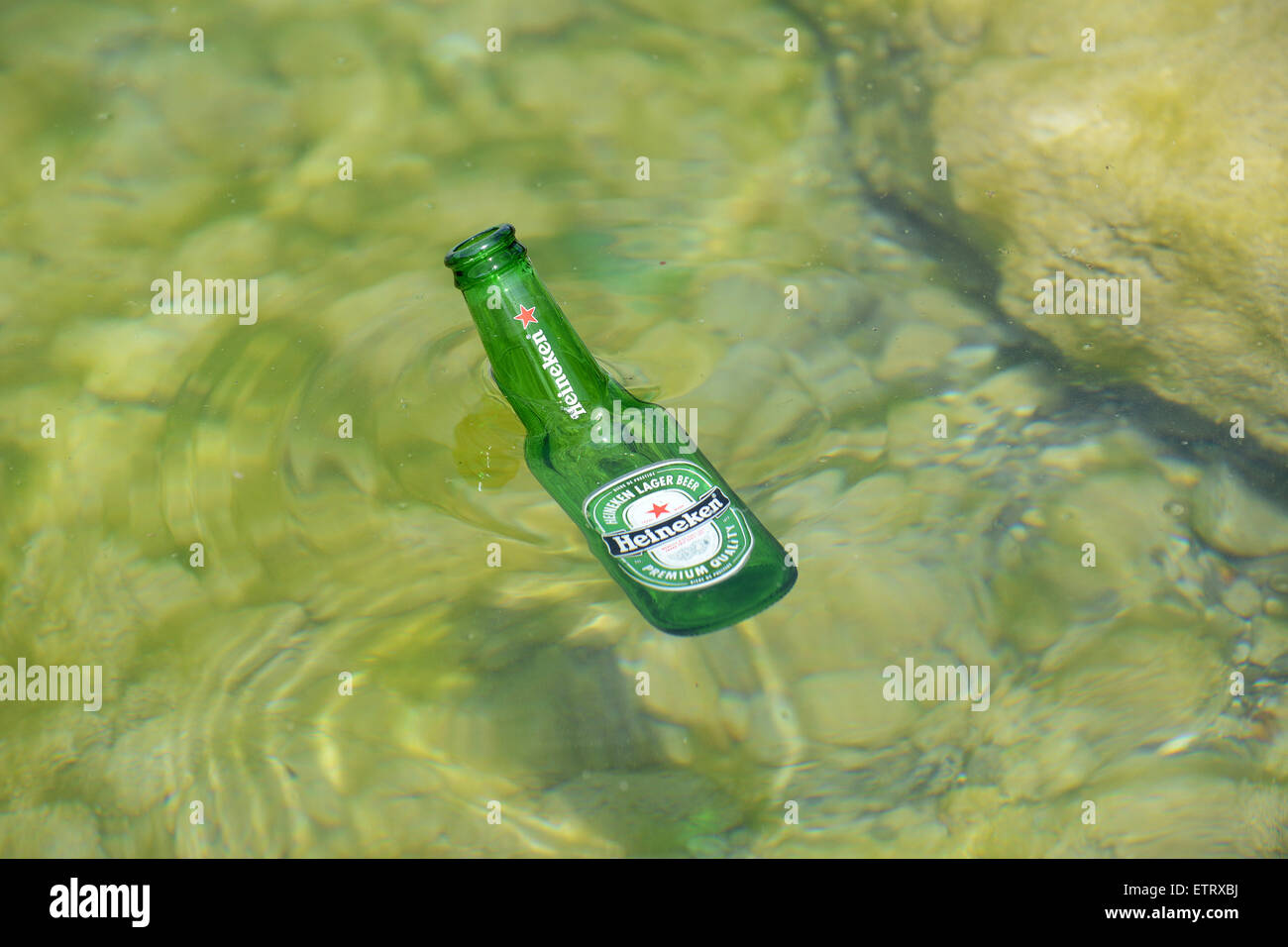 Heineken beer bottle discarded litter in sea or lake rubbish dumped dumping Stock Photo