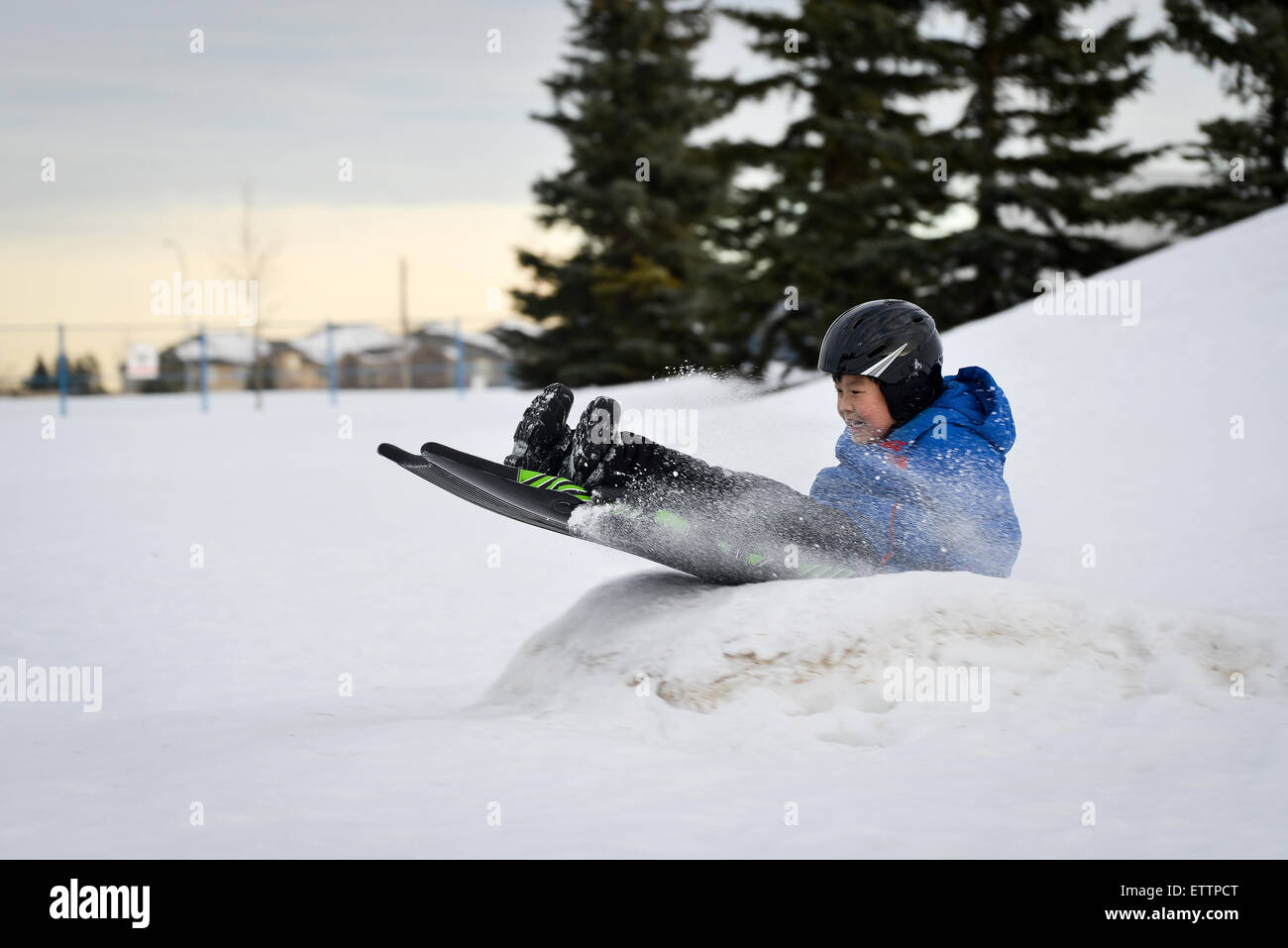 Winter Fun - Child Sledding/Tobogganing Fast Over Snow Ramp Stock Photo