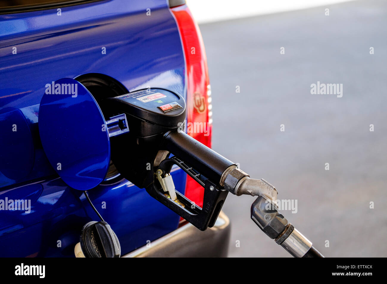 Closeup view of a gasoline nozzle fueling a blue car. USA. Stock Photo