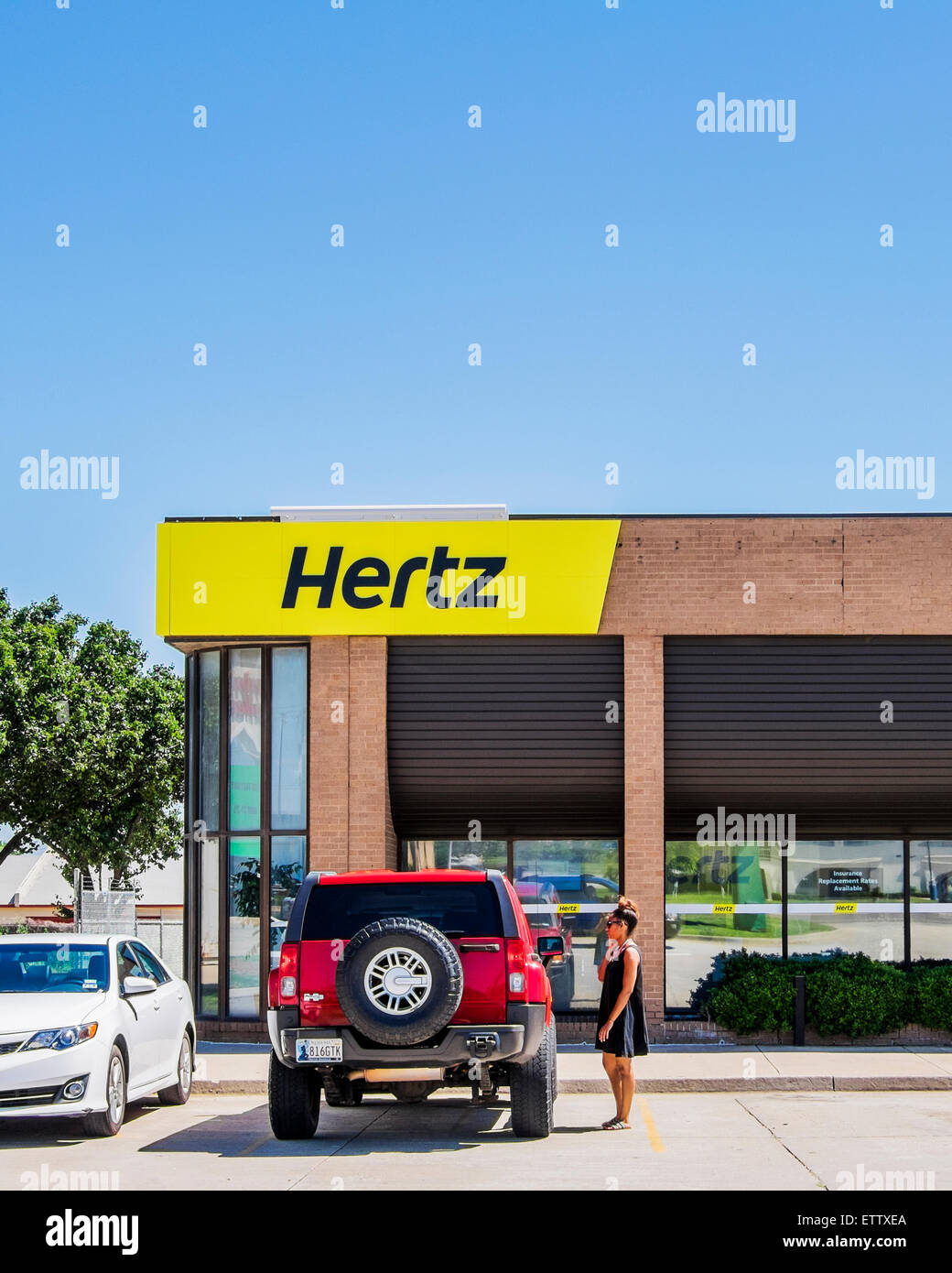 The exterior storefront of a Hertz automobile rental store with a customer in front. Oklahoma City, Oklahoma, USA. Stock Photo