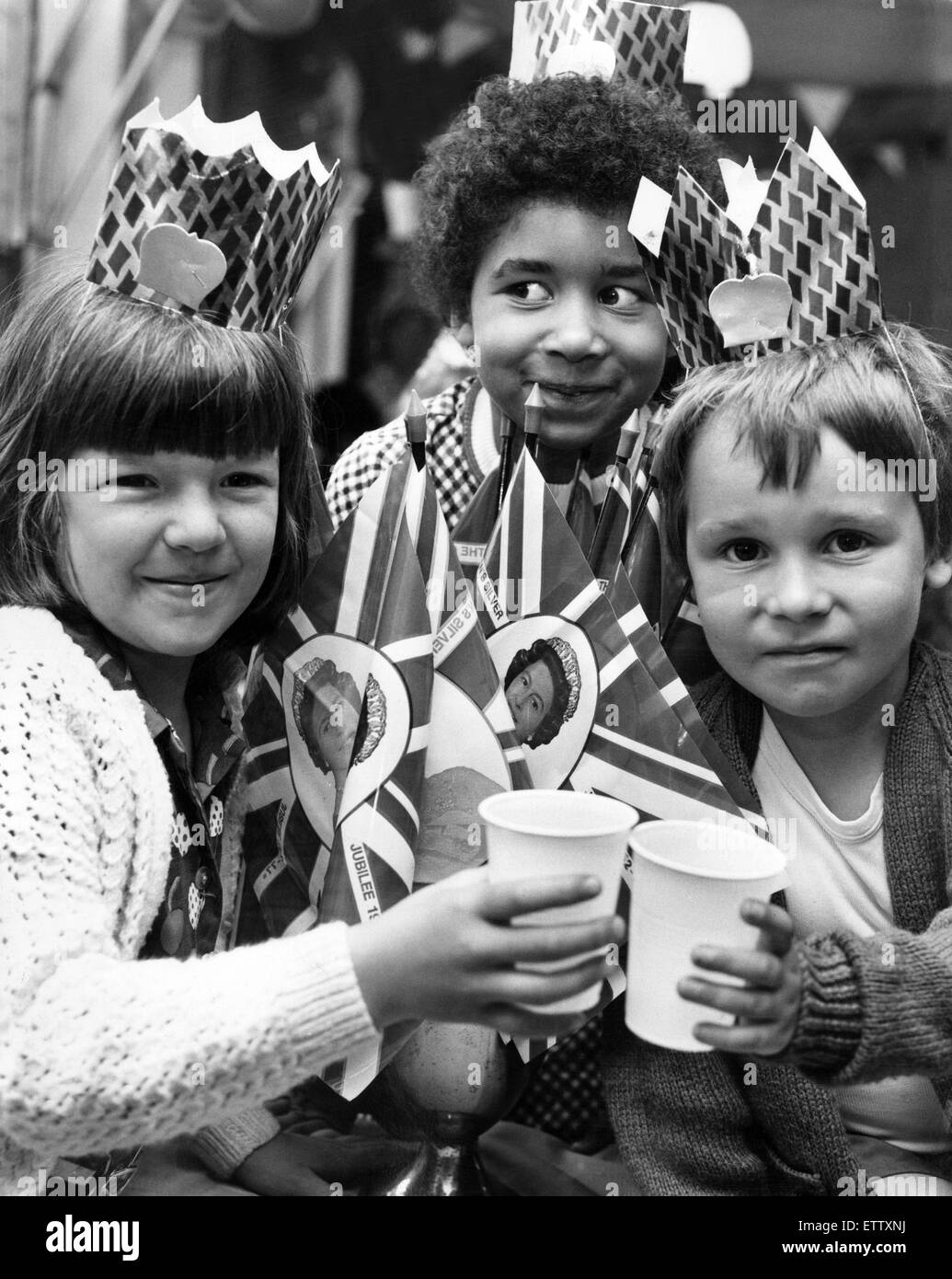 The Silver Jubilee of Elizabeth II marked the 25th anniversary of Queen Elizabeth II's accession to the throne. Showing the flag and toasting the Queen at The Nook street party, are three children who made the most of their Jubilee day. Left to right, Sar Stock Photo