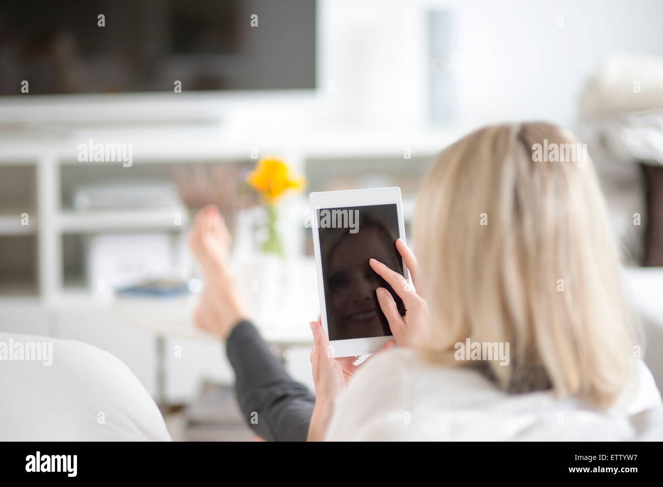 Back view of blond woman using mini tablet at home Stock Photo