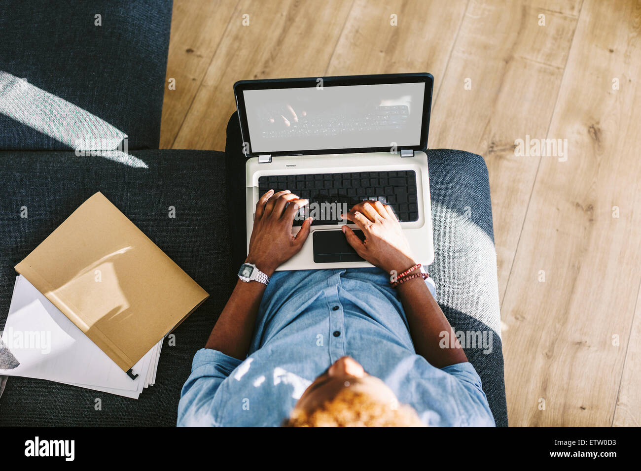 Young Afro American man sitting on couch, using laptop Stock Photo - Alamy