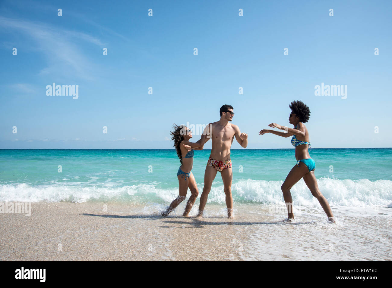 Three people playing on the beach Stock Photo