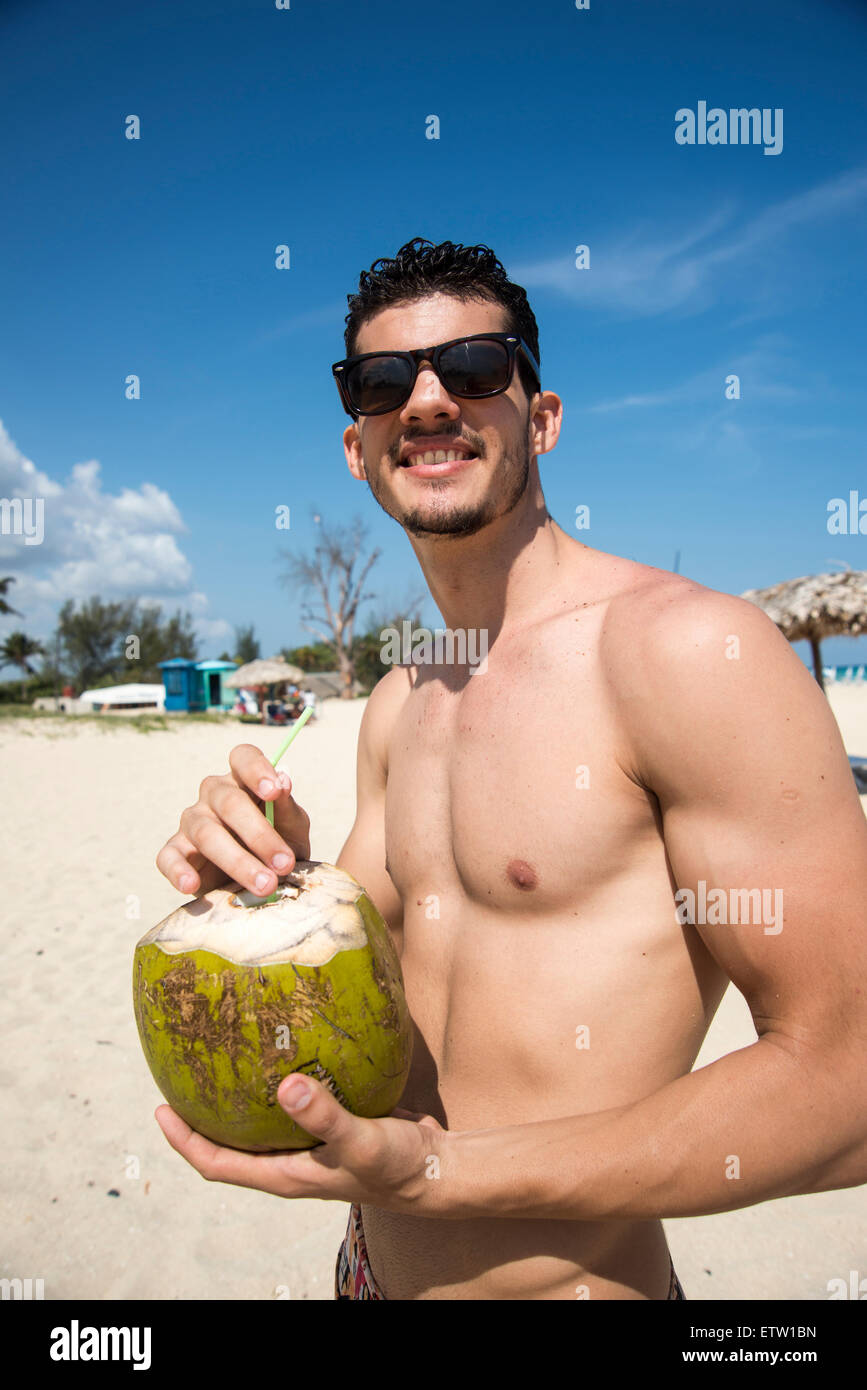 Latin man holding coconut on the beach Stock Photo