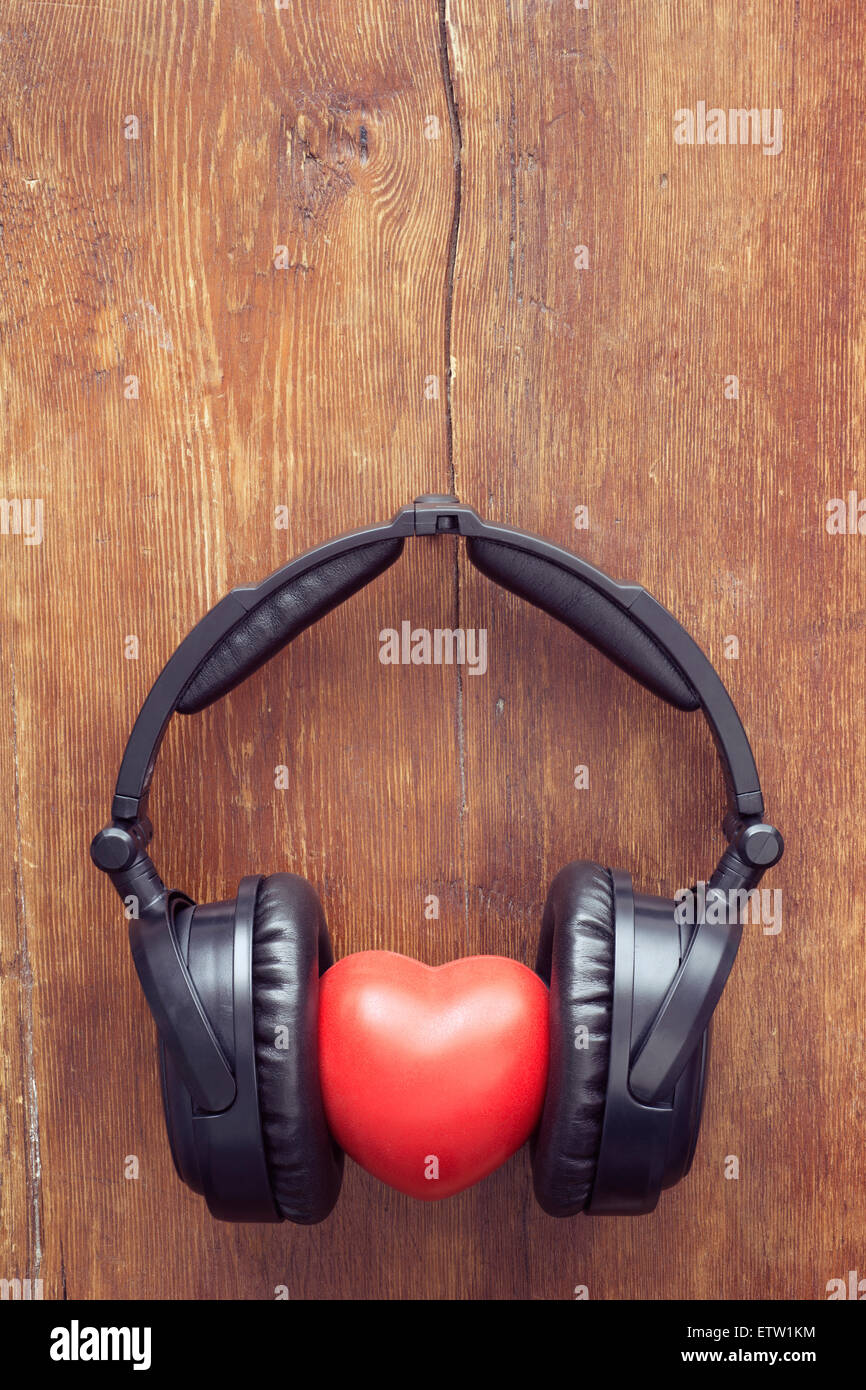 black headphones with red heart on vintage wooden background Stock Photo