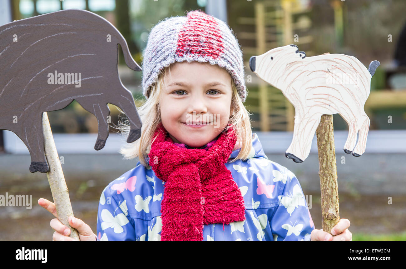 Portrait of smiling little girl holding two signs shaped like boars Stock Photo