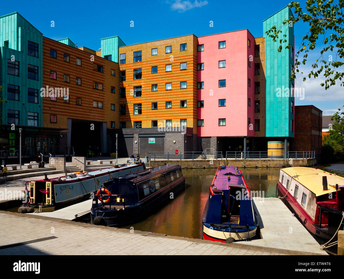 Traditional narrow boats moored next to modern buildings at a marina in Loughborough town centre Leicestershire England UK Stock Photo