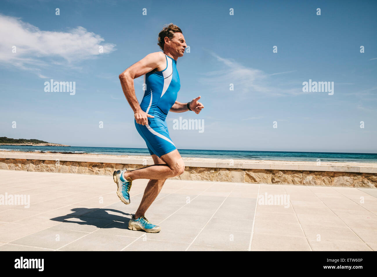 Spain, Mallorca, Sa Coma, triathlet running along beach promenade Stock Photo