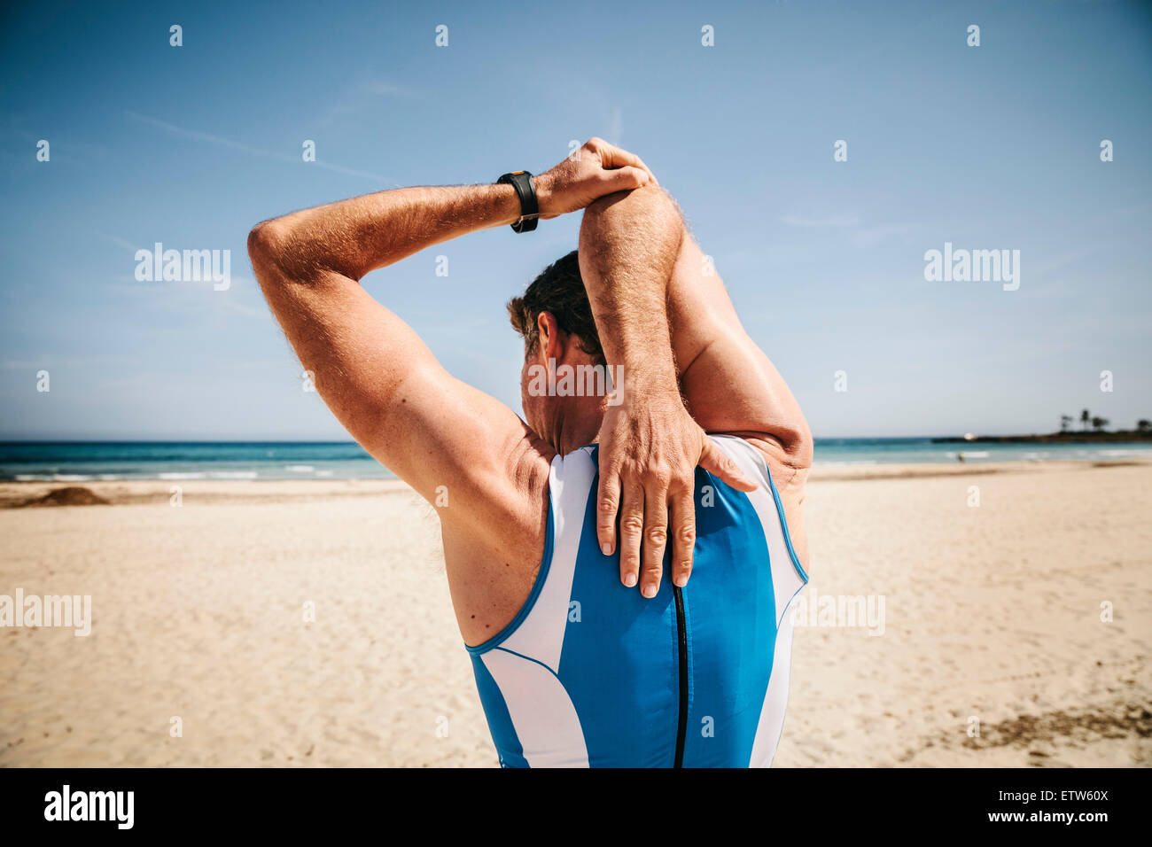 Spain, Mallorca, Sa Coma, back view of triathlet stretching on the beach Stock Photo