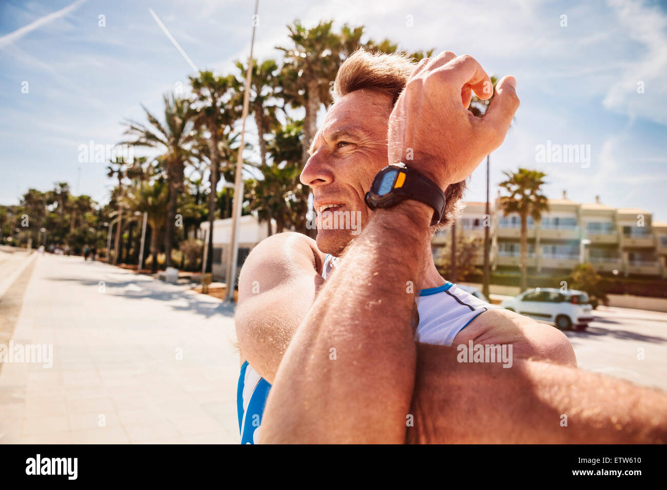 Spain, Mallorca, Sa Coma, triathlet stretching on the beach promenade Stock Photo