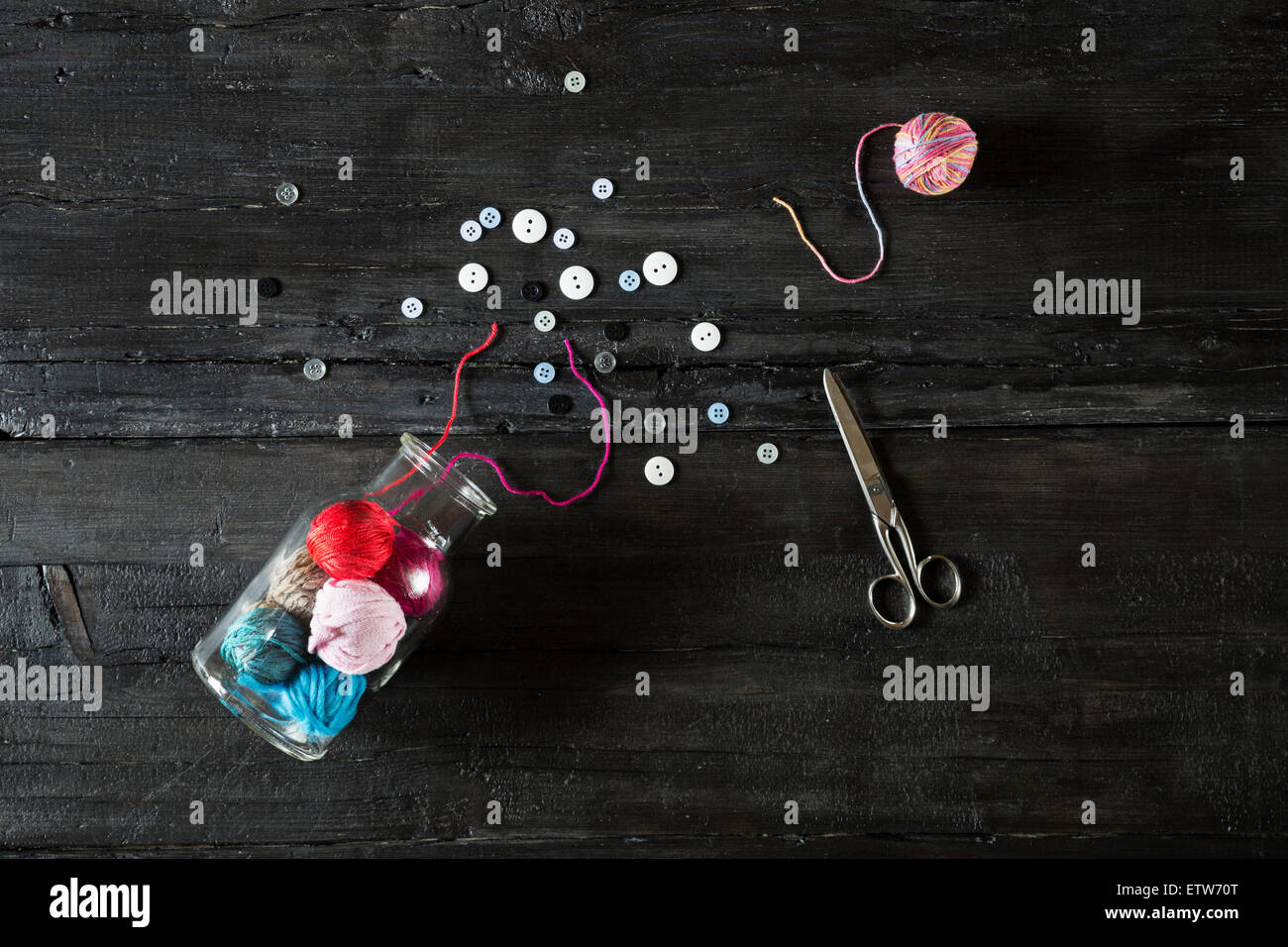 Glass of balls of wool, scissors and buttons on black wood Stock Photo ...