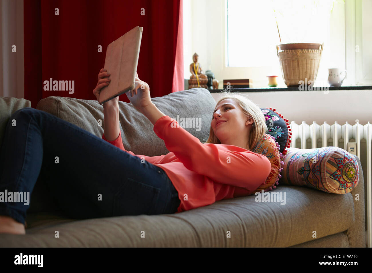 Smiling young woman relaxing with digital tablet on couch at home Stock Photo